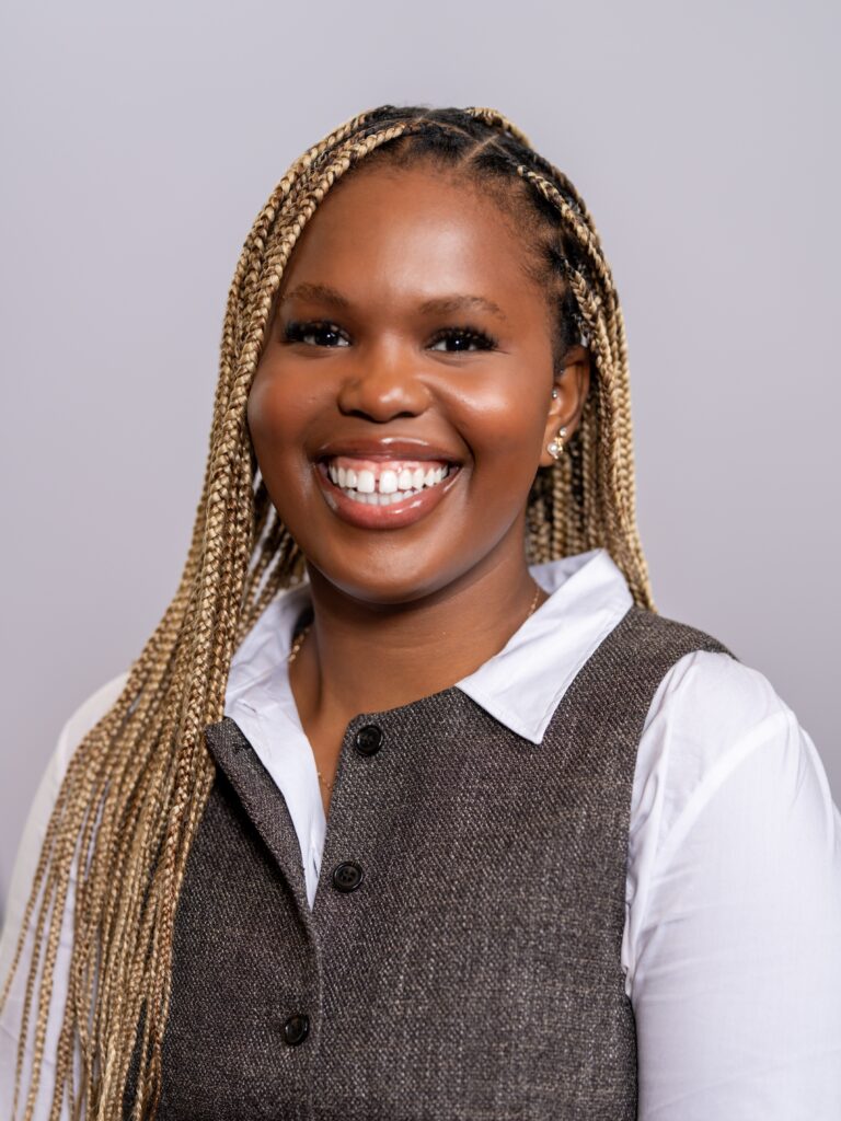 A headshot of Jahnyah Learmond with a white shirt and a beige vest. 
