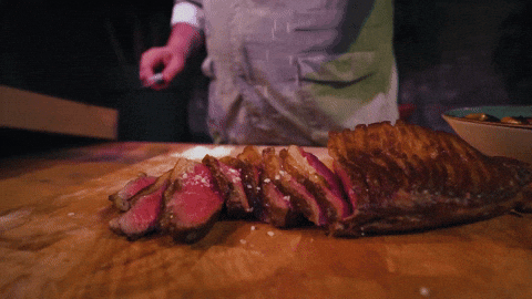 A chef sprinkling beef with salt. 