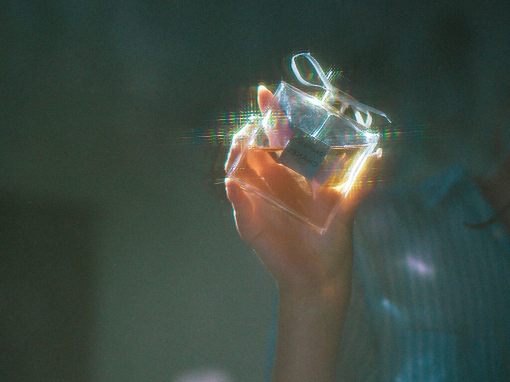 a blurry image of a hand holding up a perfume bottle
