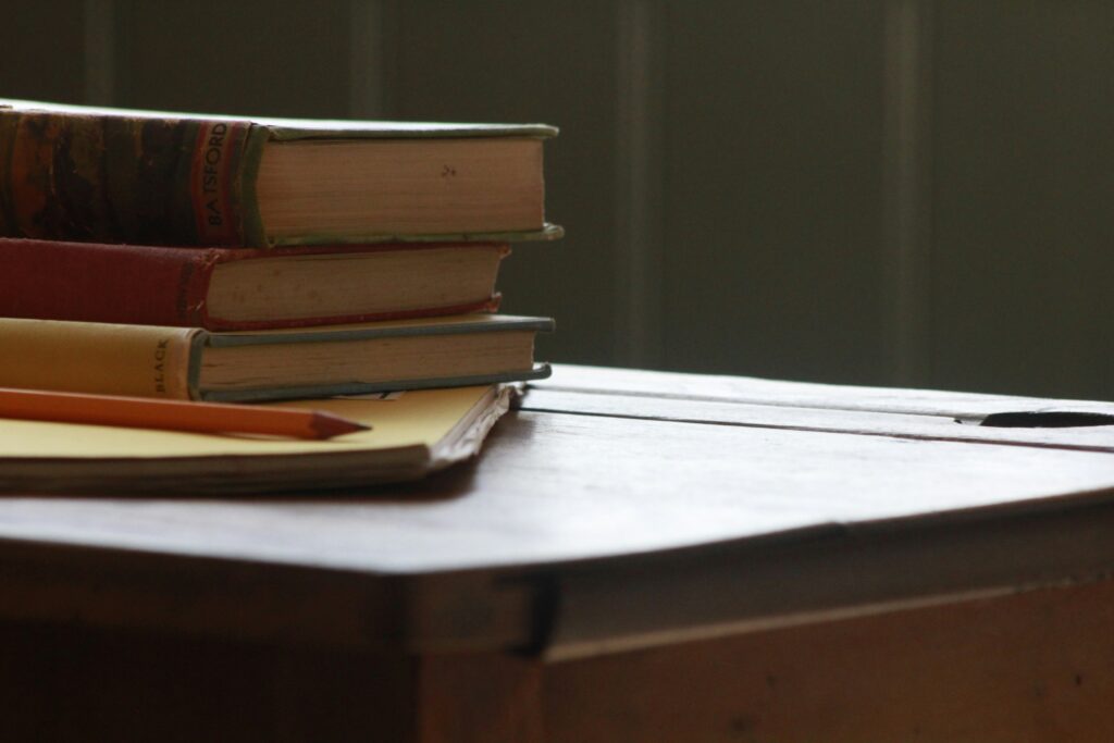 A close up photo of books kept on a study desk with a pencil nearby