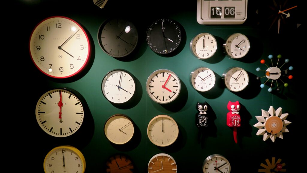 Multiple clocks placed on a green wall