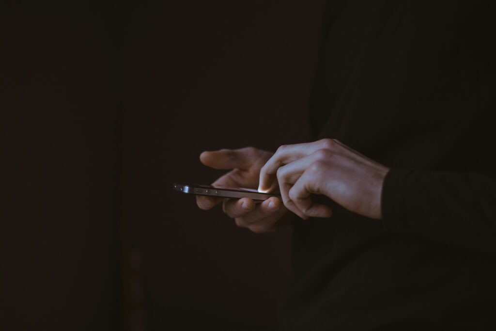A dark image of hands tapping on a phone