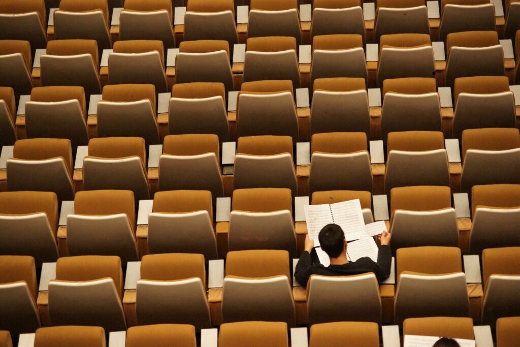 A student sitting alone in a large classroom