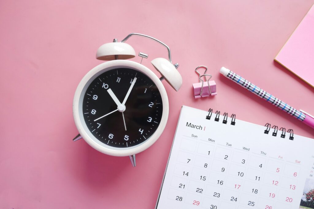 A clock and a calendar put on a bright pink background