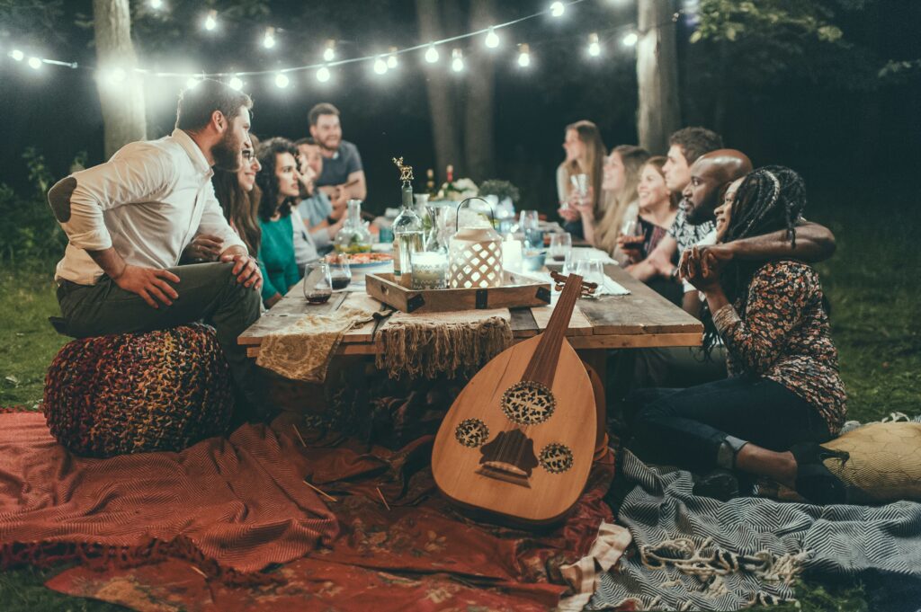 A group of people sat around a table at night with musical instruments